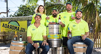 在伊斯拉莫拉达啤酒公司的招牌前，五个人拿着啤酒桶摆姿势